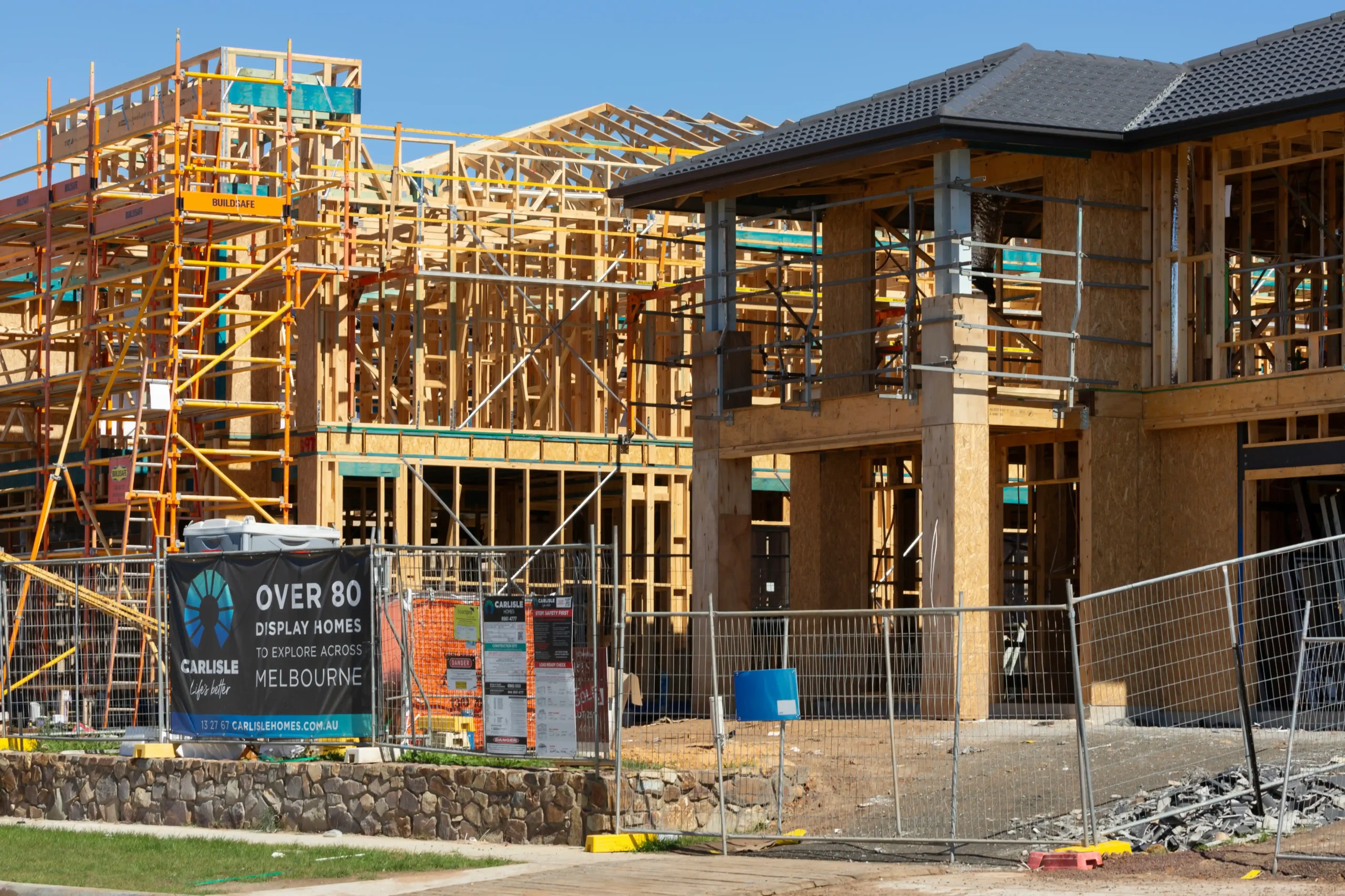 Two-storey timber house frames under construction on a display home estate